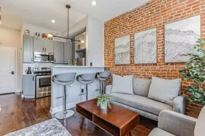 a living room with a couch and a brick wall at Studio w Terrace - Street Parking -10 min to DT in Philadelphia