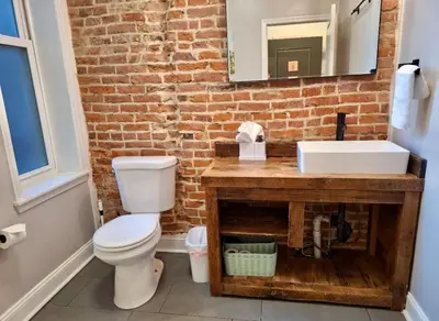 a bathroom with a toilet and a sink and a brick wall at Studio w Terrace - Street Parking -10 min to DT in Philadelphia