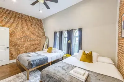 a bedroom with two beds and a brick wall at Lovely 2BR w Patio - 10 mins to DT - Sleeps 10 in Philadelphia