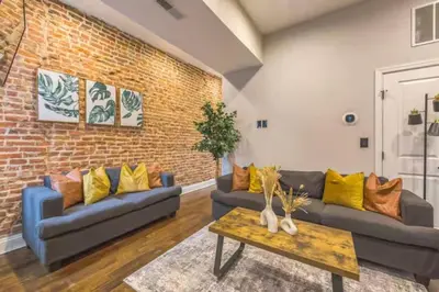 a living room with two couches and a brick wall at Lovely 2BR w Patio - 10 mins to DT - Sleeps 10 in Philadelphia