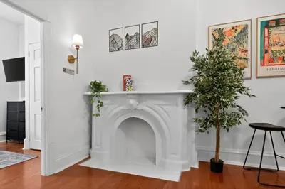 a white fireplace in a living room with a plant at Lovely 1BR Center City with King Bed and Sleeper Sofa in Philadelphia
