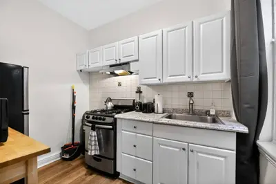 a kitchen with white cabinets and a sink and a stove at Lovely 1BR Center City with King Bed and Sleeper Sofa in Philadelphia