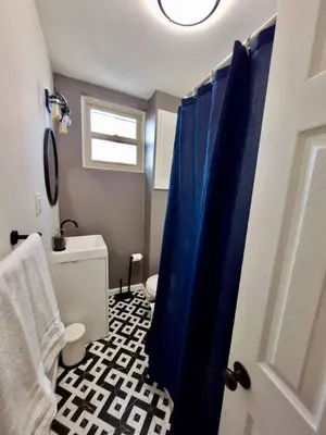 a bathroom with a toilet and a blue shower curtain at Bi-Level 3 BR plus Finished Basement that Sleeps 12 in Philadelphia