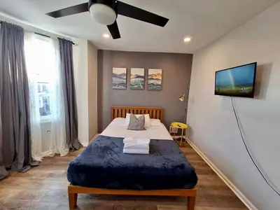 a bedroom with a large bed with a ceiling fan at Bi-Level 3 BR plus Finished Basement that Sleeps 12 in Philadelphia
