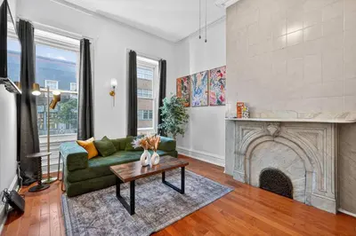 a living room with a green couch and a fireplace at Sunny 1BR in Center City with King Sized Memory Foam Sofa Bed in Philadelphia