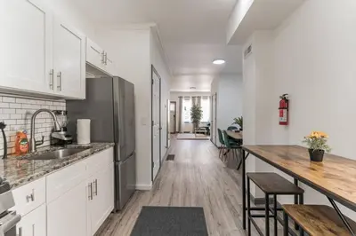 a kitchen with white cabinets and a long hallway at 5BR - Sleeps 14 - Street Parking - 10 min to DT in Philadelphia