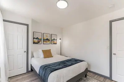 a white bedroom with a bed and two pictures on the wall at 5BR - Sleeps 14 - Street Parking - 10 min to DT in Philadelphia