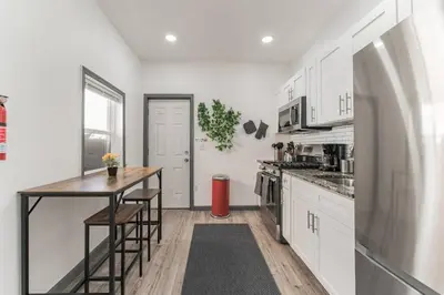 a kitchen with white cabinets and a wooden table at 5BR - Sleeps 14 - Street Parking - 10 min to DT in Philadelphia