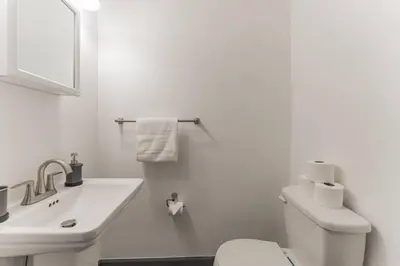 a white bathroom with a toilet and a sink at 5BR - Sleeps 14 - Street Parking - 10 min to DT in Philadelphia