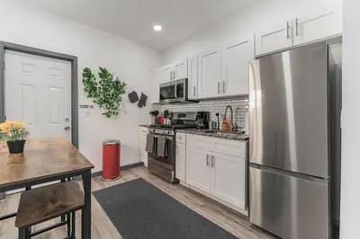 a kitchen with white cabinets and a stainless steel refrigerator at 5BR - Sleeps 14 - Street Parking - 10 min to DT in Philadelphia