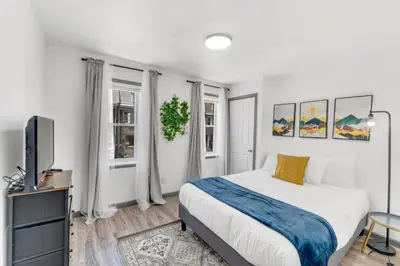 a white bedroom with a bed and a tv at 5BR - Sleeps 14 - Street Parking - 10 min to DT in Philadelphia