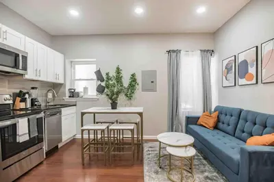 a living room with a blue couch and a kitchen at Charming Center City 2BR - Sleeps 8 people in Philadelphia