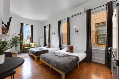 a room with two beds and a couch and windows at New Studio in Center City that Sleeps 4 with Fast Wifi in Philadelphia