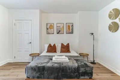 a white bedroom with a large bed with orange pillows at Large and Cozy Center City 1BR in Philadelphia