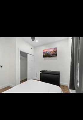 a bedroom with a white bed and a painting on the wall at Modern 2 bedroom 1 bath unit 2 Near Airport, Xfinity Arena and Eagles Stadium in Philadelphia