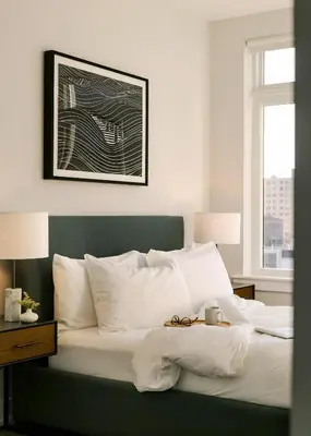 a bedroom with a bed with white pillows and a window at Sosuite at The Ovation - Ave of The Arts in Philadelphia