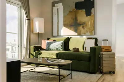 a living room with a green couch and a table at Sosuite at The Ovation - Ave of The Arts in Philadelphia