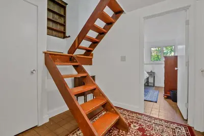a wooden staircase in a living room with a door at House Under The Cliff in New Paltz