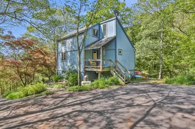 a blue house in the middle of a road at House Under The Cliff in New Paltz