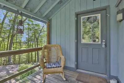 a wicker chair sitting on a porch with a door at House Under The Cliff in New Paltz