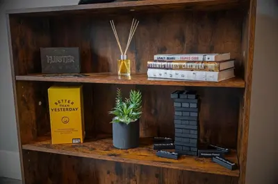 a book shelf with books and a plant on it at Cozy Desert Den 10 Min Downtown& 6 Min Brewerytown in Philadelphia