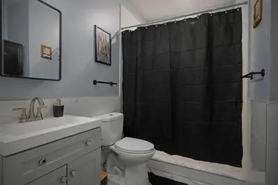 a bathroom with a black shower curtain and a toilet at Cozy Desert Den 10 Min Downtown& 6 Min Brewerytown in Philadelphia