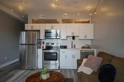 a kitchen with white cabinets and a couch and a table at Cozy Desert Den 10 Min Downtown& 6 Min Brewerytown in Philadelphia