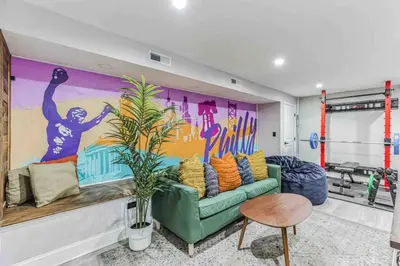 a living room with a green couch and a mural at Large Bi-Level 3BR w Patio - 10 min to DT in Philadelphia