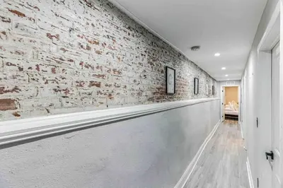 a hallway with a white brick wall and a white hallway at Large Bi-Level 3BR w Patio - 10 min to DT in Philadelphia