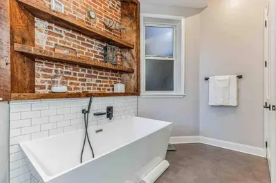 a bathroom with a white tub and a brick wall at Large Bi-Level 3BR w Patio - 10 min to DT in Philadelphia
