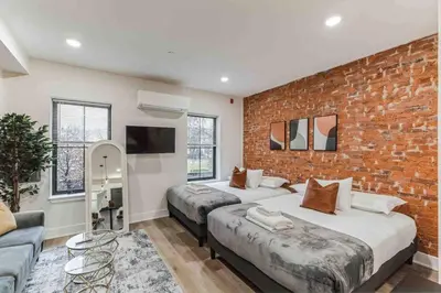 a bedroom with two beds and a brick wall at Stylish Studio Sleeps Four - 10 mins to DT (B) in Philadelphia