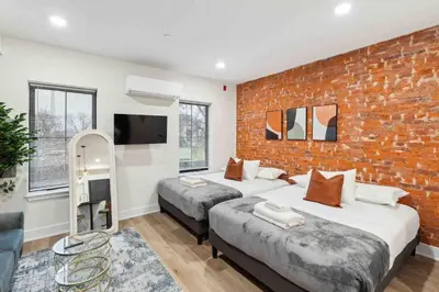 two beds in a room with a brick wall at Stylish Studio Sleeps Four - 10 mins to DT (B) in Philadelphia