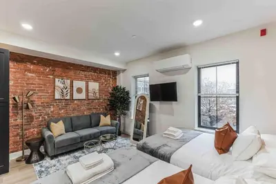 a room with a bed and a couch and a brick wall at Stylish Studio Sleeps Four - 10 mins to DT (B) in Philadelphia