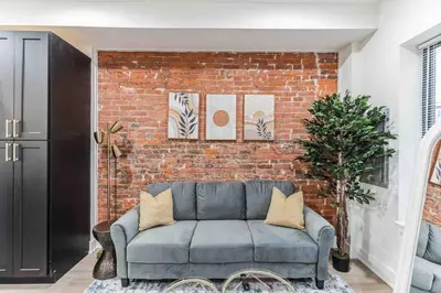 a brick wall with a couch in a living room at Stylish Studio Sleeps Four - 10 mins to DT (B) in Philadelphia