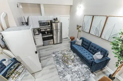 a living room with a blue couch and a kitchen at Large Bi-Level 2BR Loft in Old City that Sleeps 8 in Philadelphia