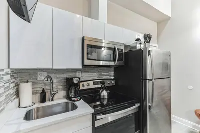 a kitchen with a sink and a stainless steel refrigerator at Large Bi-Level 2BR Loft in Old City that Sleeps 8 in Philadelphia