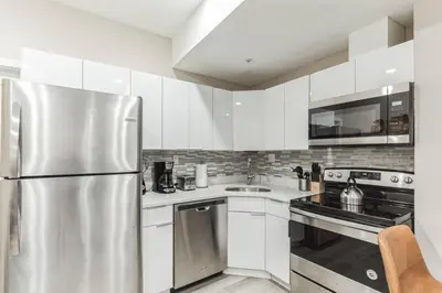 a kitchen with white cabinets and a stainless steel refrigerator at Large 2BR in Old City that Sleeps 8 in Philadelphia