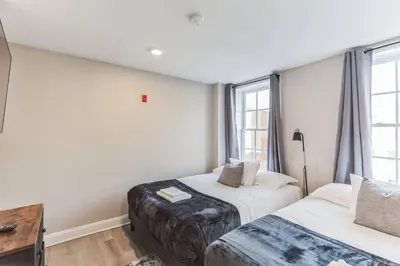 a bedroom with two beds and a desk and windows at Large 2BR in Old City that Sleeps 8 in Philadelphia