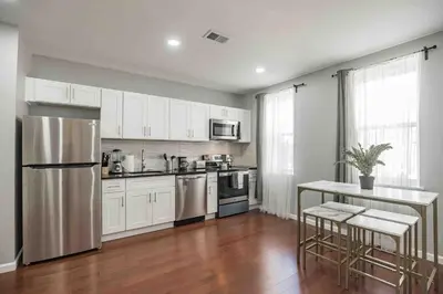 a kitchen with white cabinets and a stainless steel refrigerator at Large and Sunny 1BR - Center City - Sleeps 4 in Philadelphia