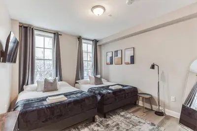 a bedroom with two beds and a large window at Bi-Level 2BR Loft in Old City in Philadelphia