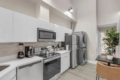 a kitchen with white cabinets and a stainless steel refrigerator at Bi-Level 2BR Loft in Old City in Philadelphia
