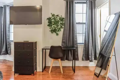 a black desk and a chair in a room with windows at Cozy Studio across from Convention Center - 4R in Philadelphia