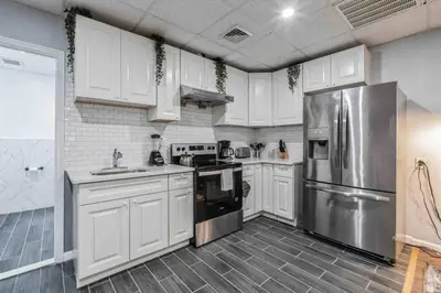 a kitchen with white cabinets and a stainless steel refrigerator at BRAND NEW Modern 2BR - Heart of Center City in Philadelphia
