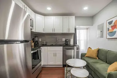 a kitchen with white cabinets and a green couch at Cozy 1BR - Center City - Sleeps 4 - 2 Beds in Philadelphia