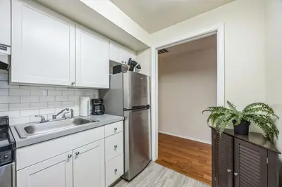 a kitchen with white cabinets and a stainless steel refrigerator at Large and Sunny 1BR Located Near Rittenhouse Square in Philadelphia