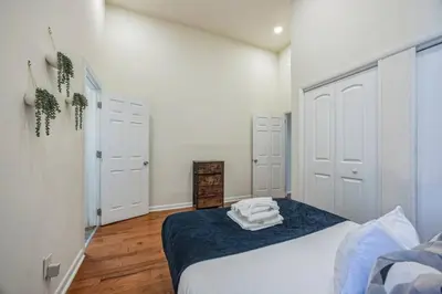 a bedroom with a bed with white walls and wooden floors at Large and Sunny 1BR Located Near Rittenhouse Square in Philadelphia