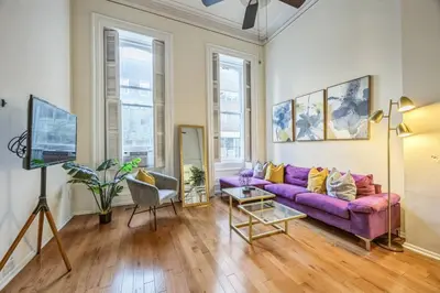 a living room with a purple couch and some windows at Large and Sunny 1BR Located Near Rittenhouse Square in Philadelphia
