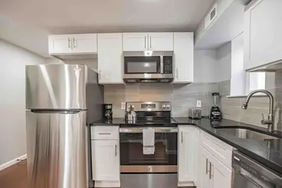 a kitchen with white cabinets and a stainless steel refrigerator at Modern and Stylish Center City 1BR - Perfect Location in Philadelphia