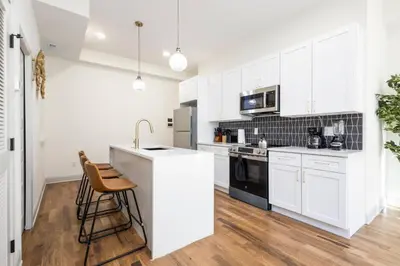 a white kitchen with white cabinets and a sink at 2BR - Fairmount Park -10 mins to DT - Sleeps 10 in Philadelphia
