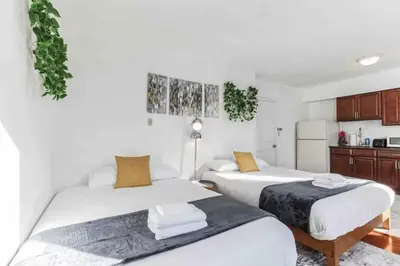 two beds in a room with white walls and wooden cabinets at Spring Garden Small and Cozy Studio Sleeps 4 in Philadelphia